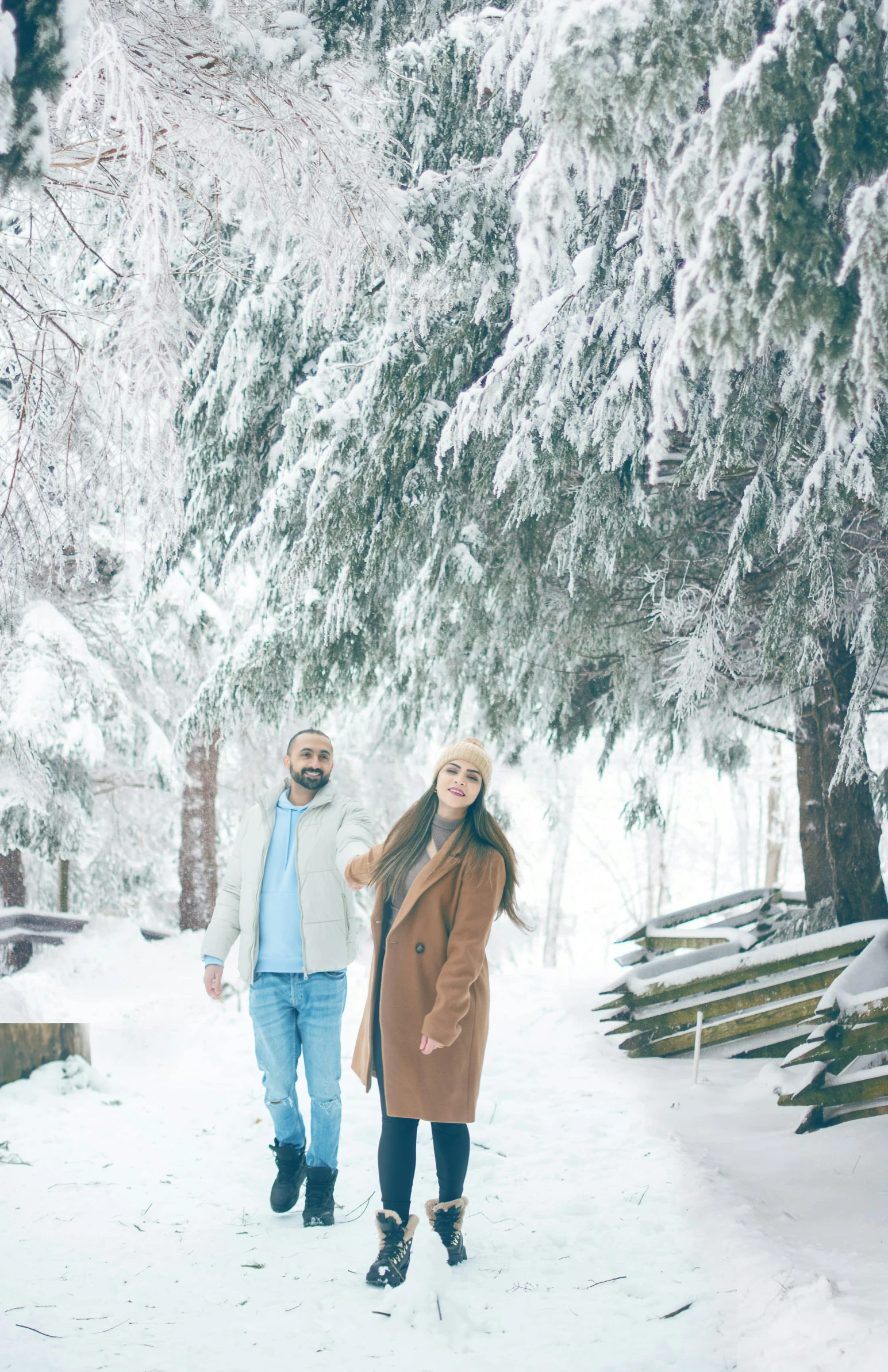 a man and a woman standing under a tree in the snow