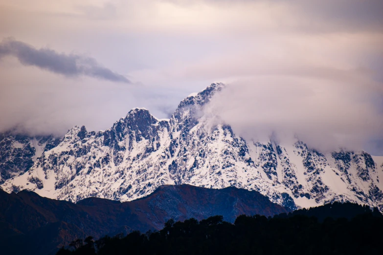 a mountain covered in snow under cloudy skies