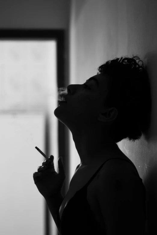 a woman holding a cigarette next to a wall