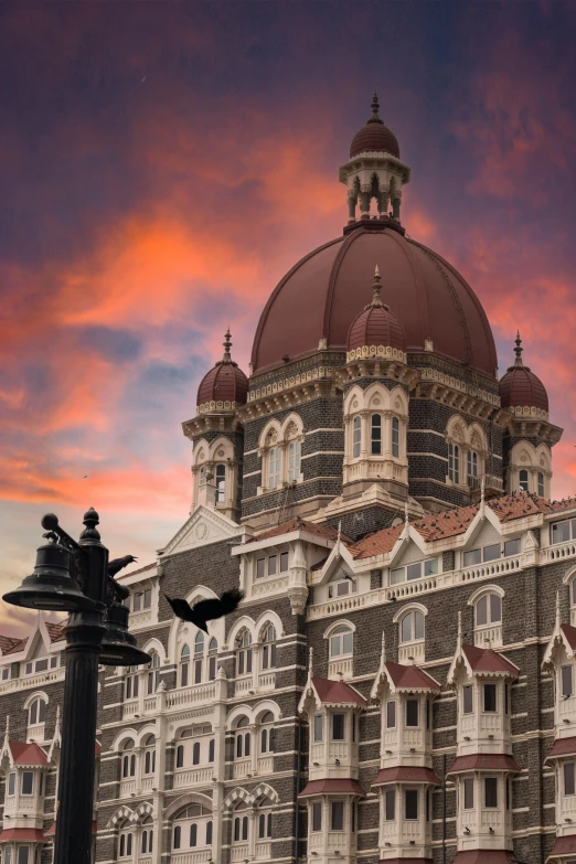 an ornate building with turrets on top under a pink and blue sky