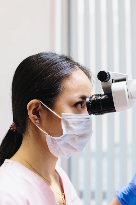 woman looking through a binocycope at an eye exam