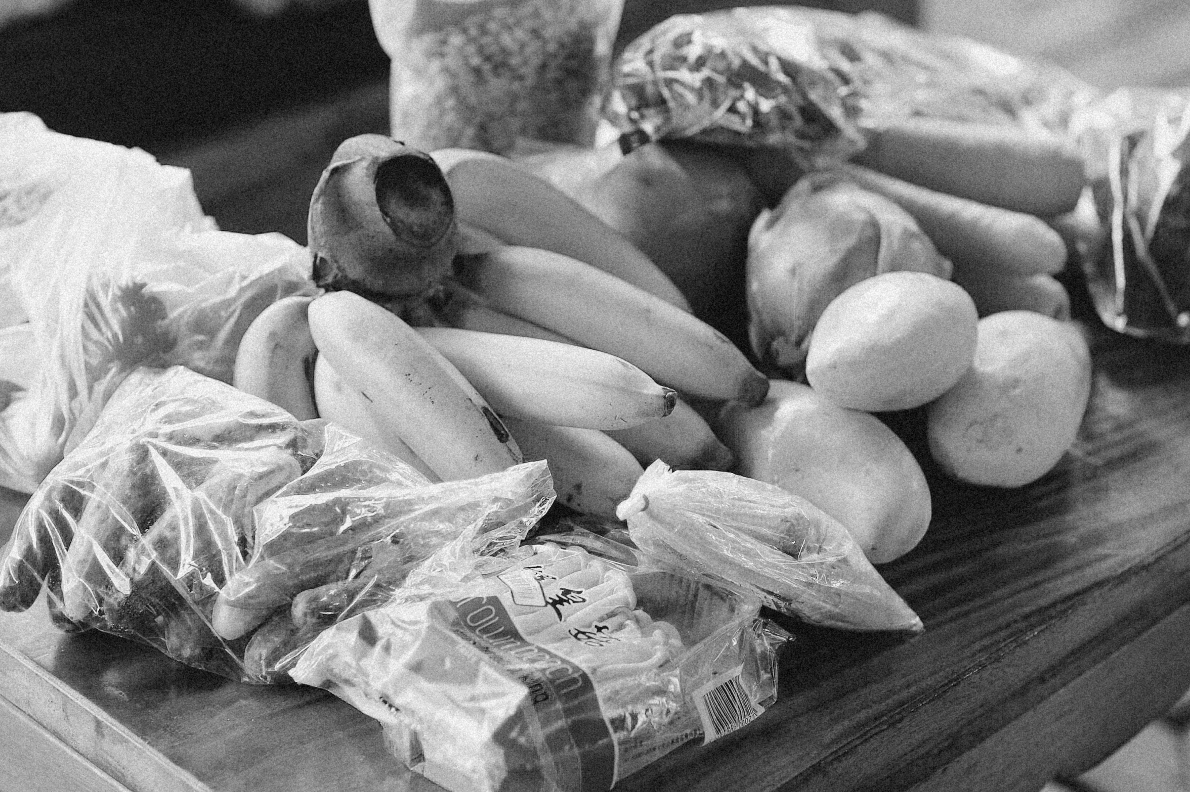 a bunch of bananas are next to a bundle of dogs and potatoes