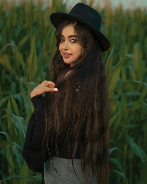 woman in long dress and black hat standing near field