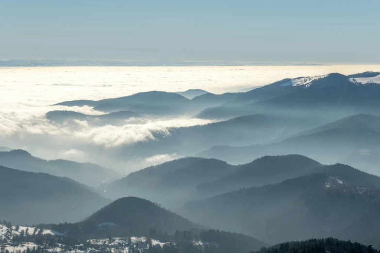 mountains surrounded by fog with a sky in the background