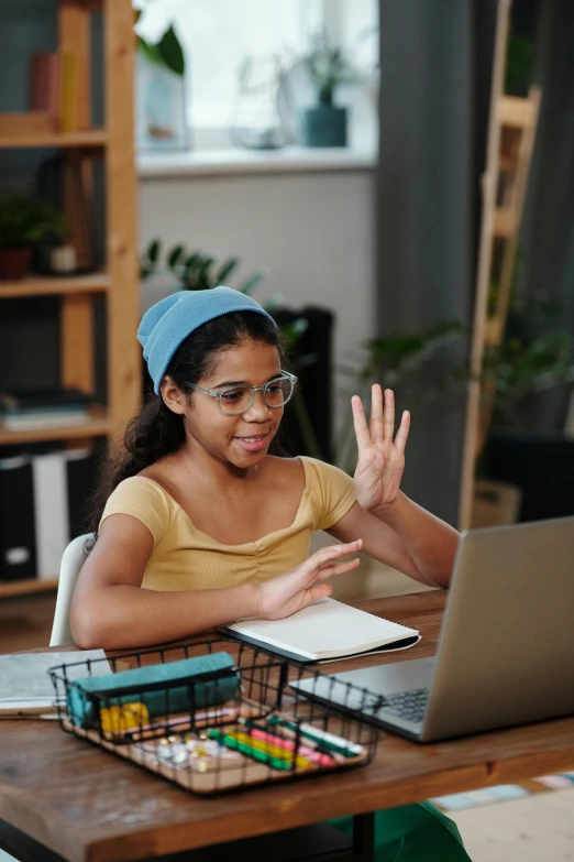 little girl sitting at a table using a laptop computer