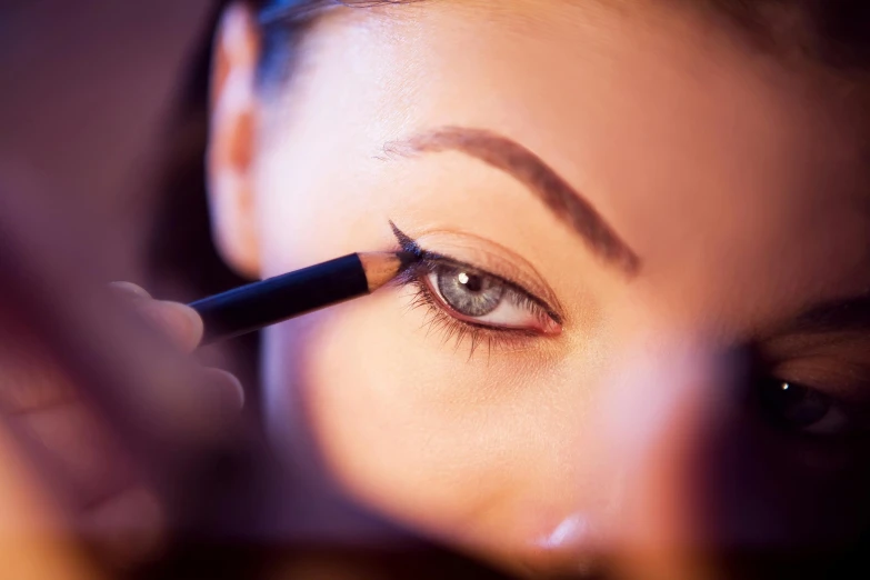 a woman is doing eyeliners while using a brush