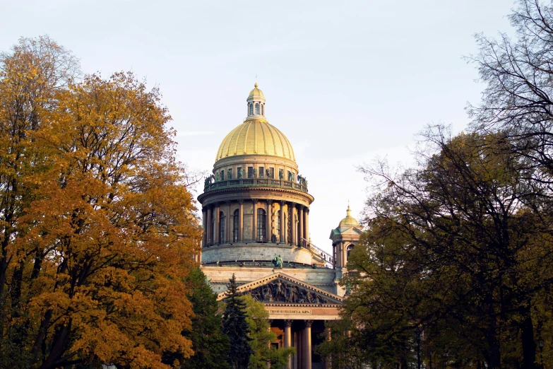 the dome of the old stone building is surrounded by trees with orange leaves