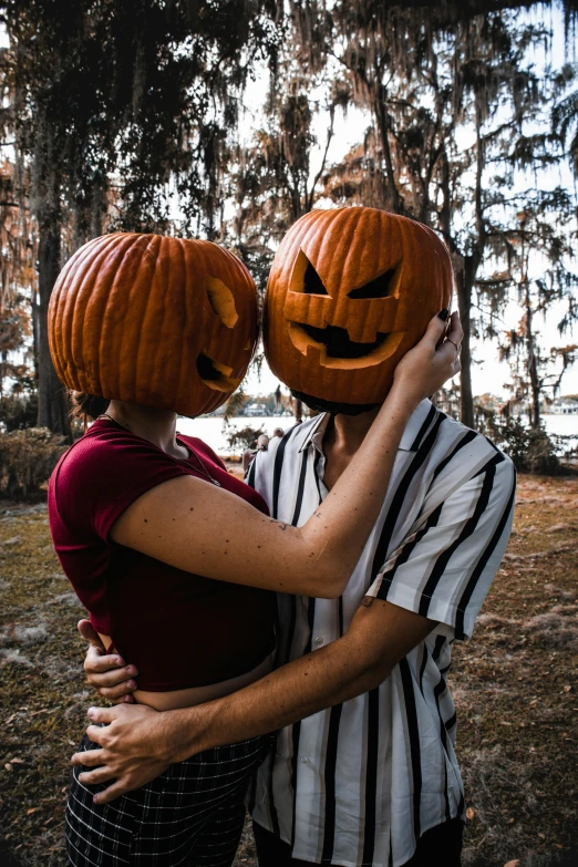 two people are holding out their faces decorated with pumpkins