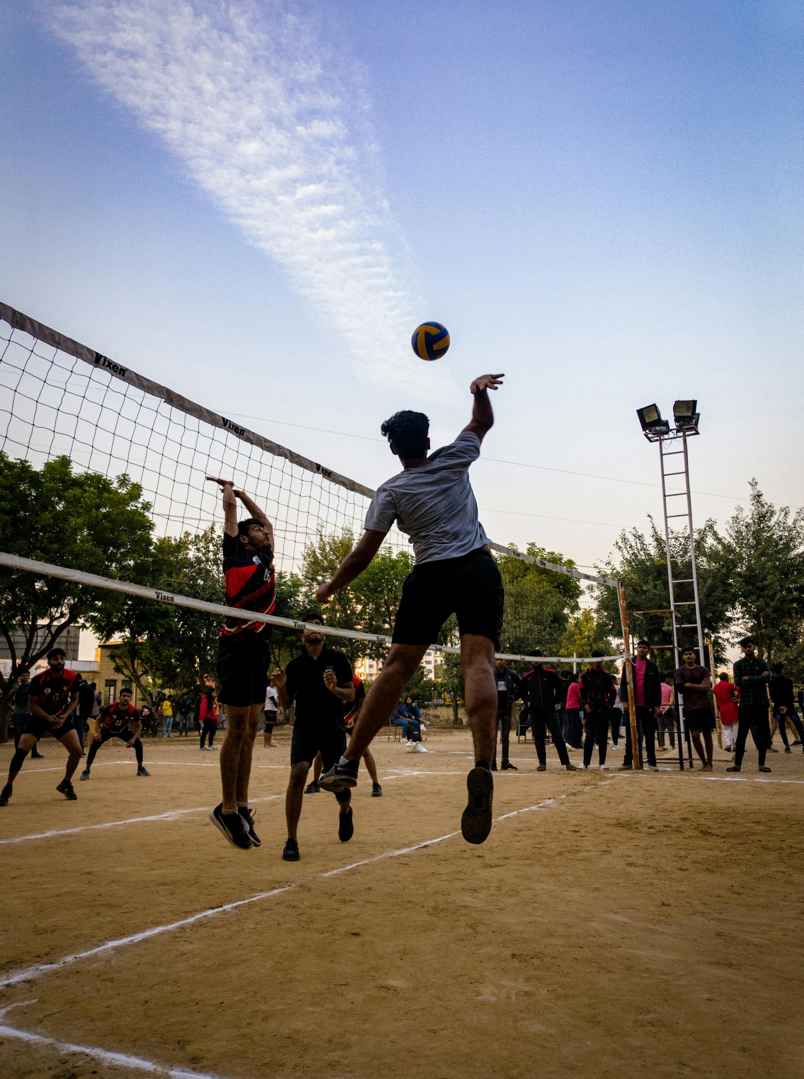 some people are playing volleyball while other people watch