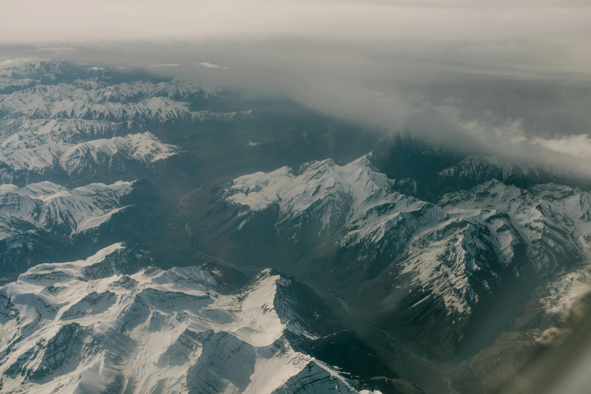 looking out the window of an airplane at a snowy mountain range