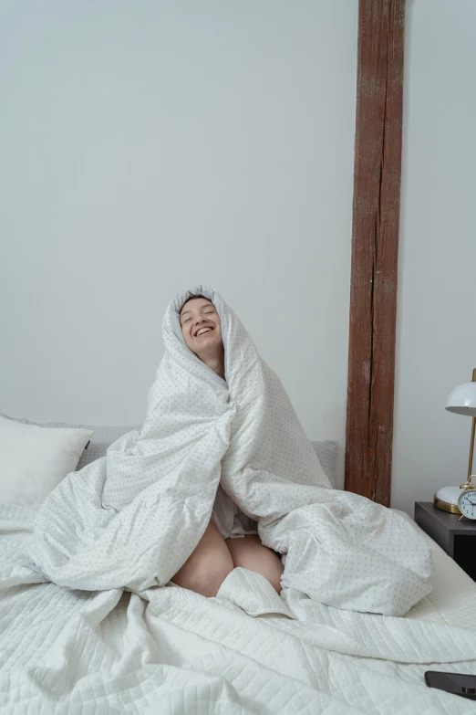 a man laying on top of a bed under a white cover