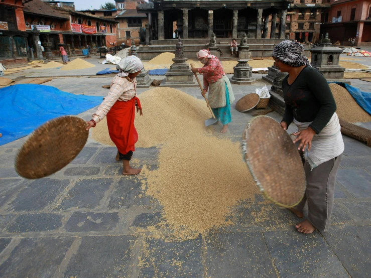 a group of women holding grain bags and talking to each other