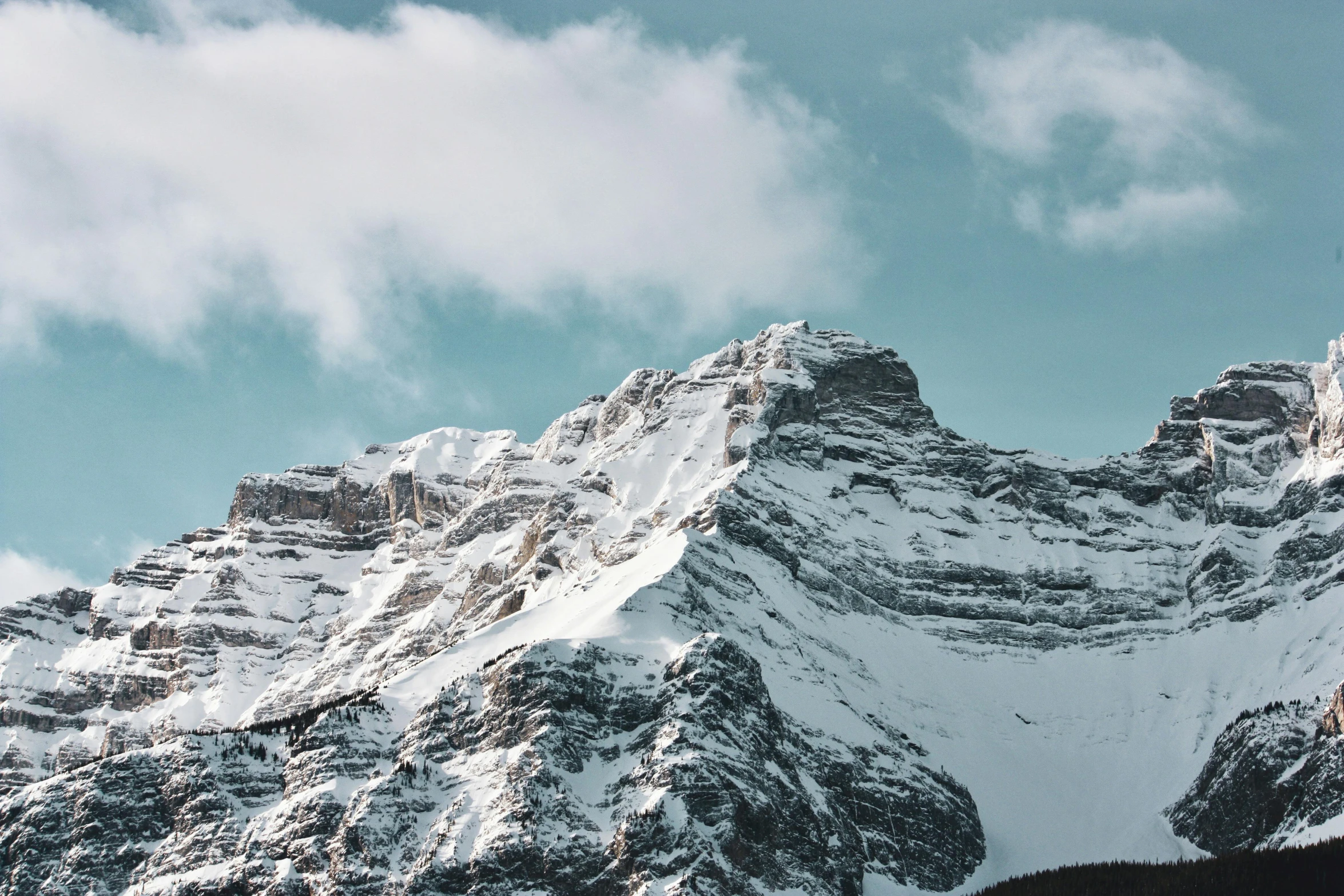 the top of a mountain with snow covered mountains