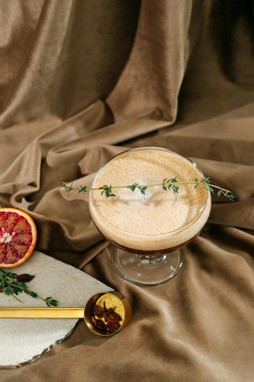 an orange martini, rosemary sprig and a golden stick are ready to be served