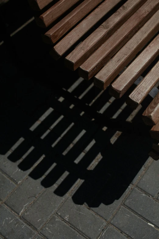 a shadow of the sun from a bench onto the ground