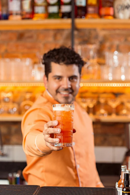 a man in an orange shirt pouring soing into a glass