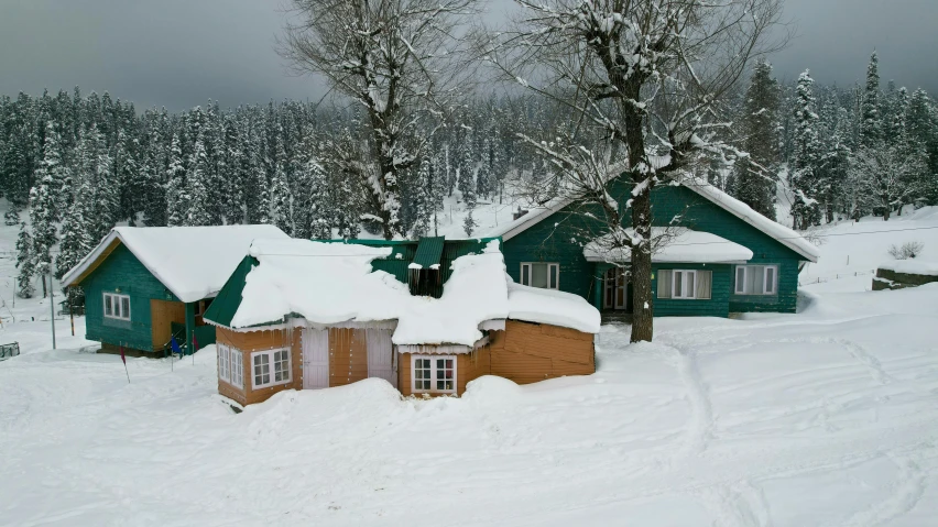 a snow covered road leading to a green cabin