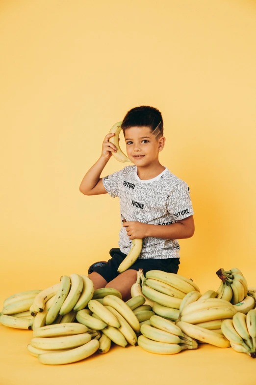 a little boy that is sitting on some bananas