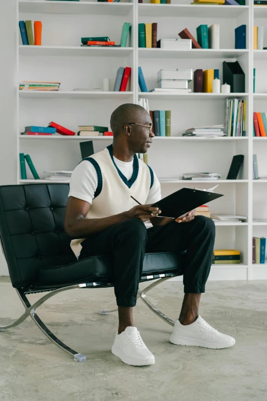 a man sitting in a chair reading and holding a book