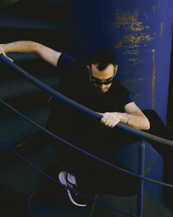 a man sitting on top of blue steps with his arms resting on the edge