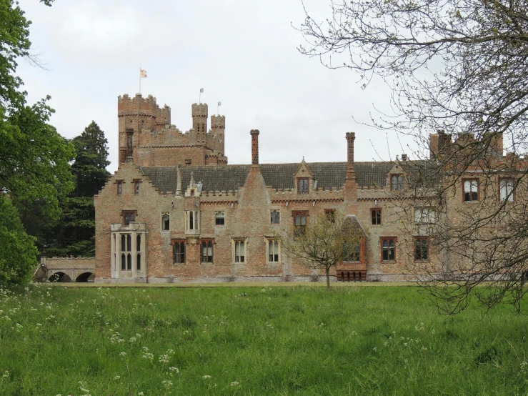 there is a brown stone building on a grassy field