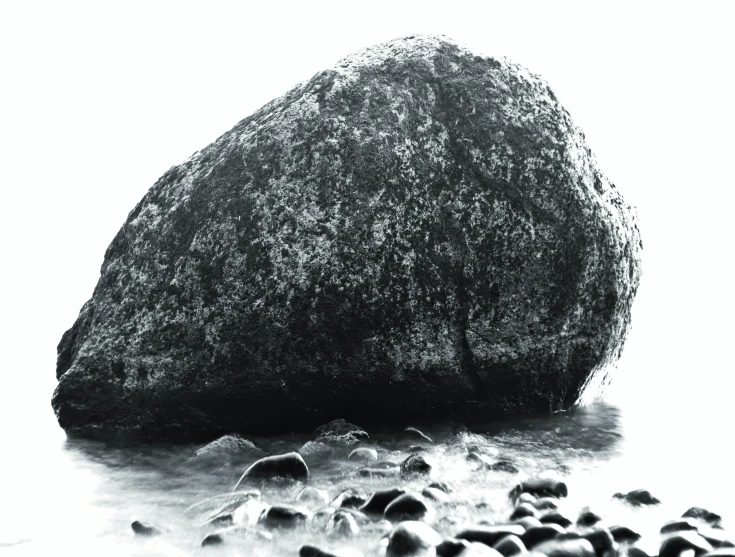 black and white pograph of a rock and waves