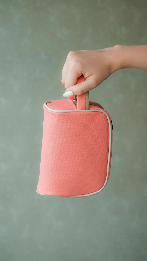 hand holding pink paper lantern against green background