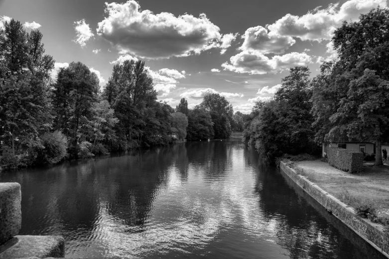 a small river on a sunny day with some clouds in the sky