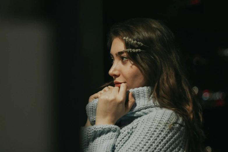 a woman standing next to a wall with her chin resting on a hand