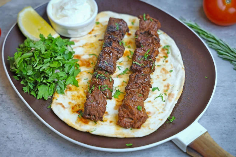 a plate of food including a skewered steak and vegetables