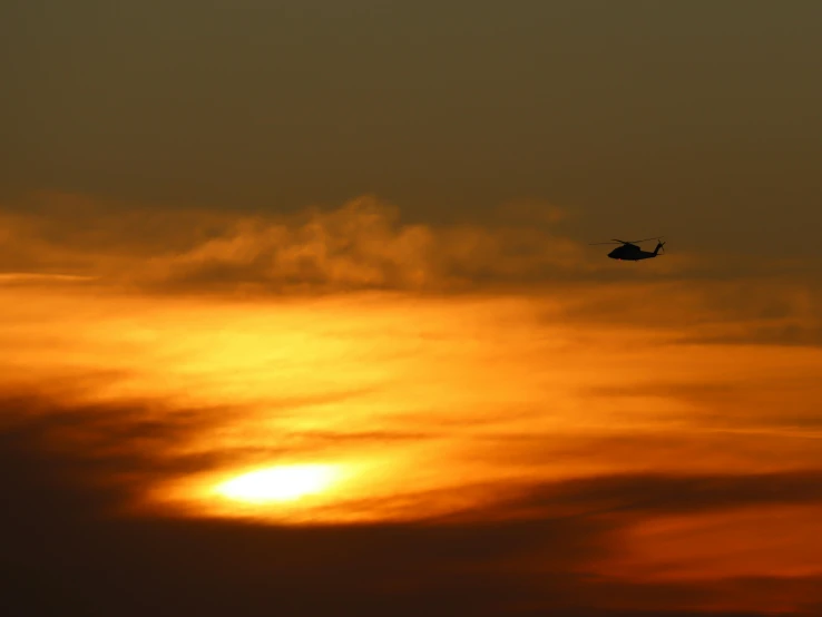 a small airplane flying in the sky against a bright orange sunset