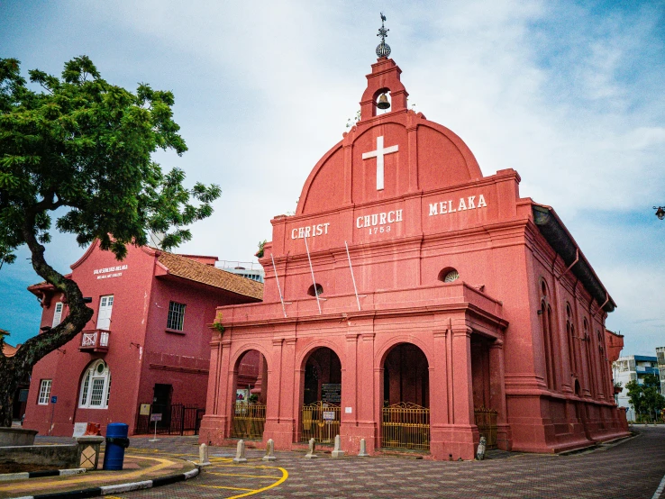 a church that is red, and has a white cross on the front