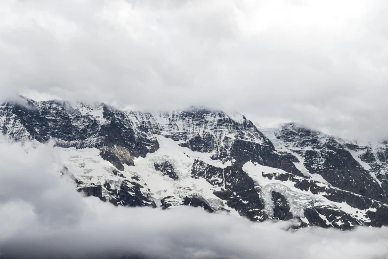 some clouds are covering the mountain and it looks to be snowy