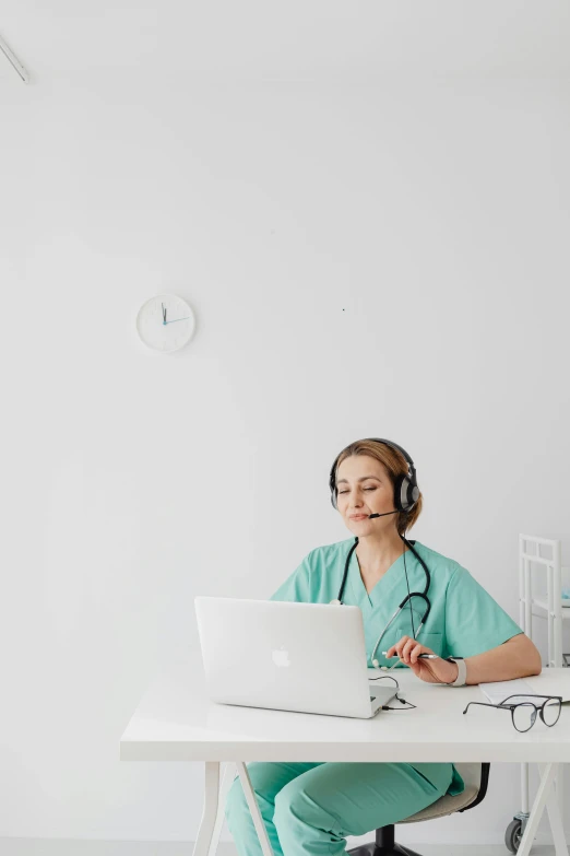 a nurse sitting at a table with a laptop computer and headphones