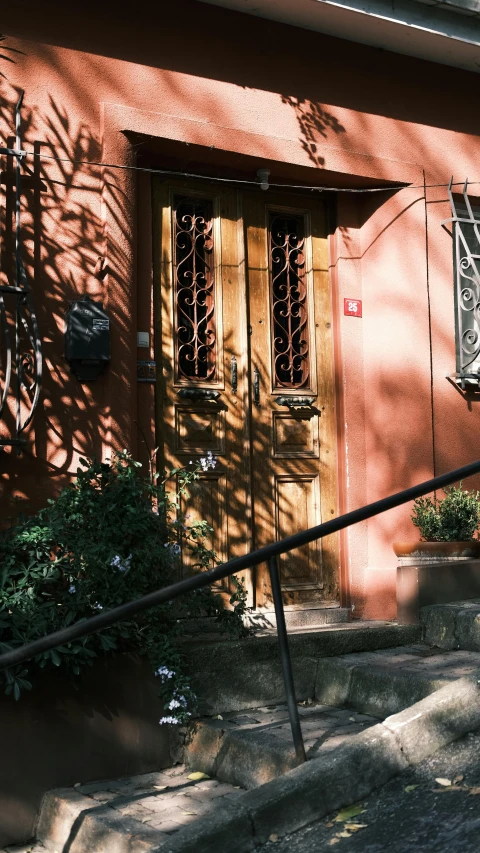 a red house with a black iron door and a set of stairs next to it