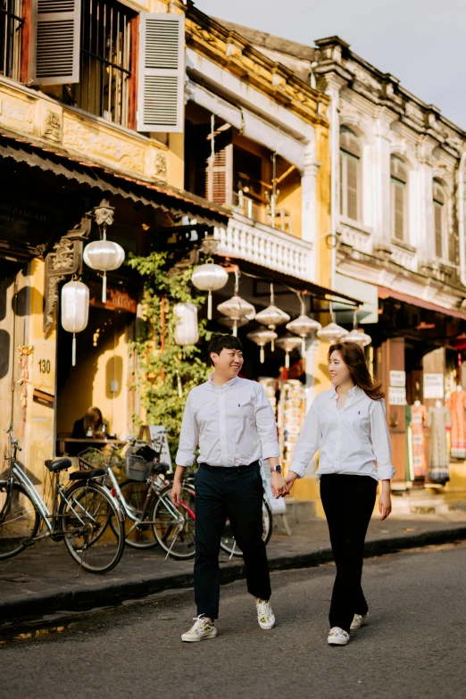 a man and woman are holding hands while walking down the street