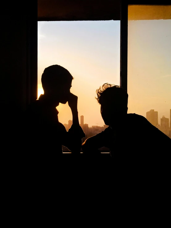 two people that are sitting in front of some windows