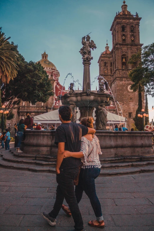 two people are walking around by a fountain