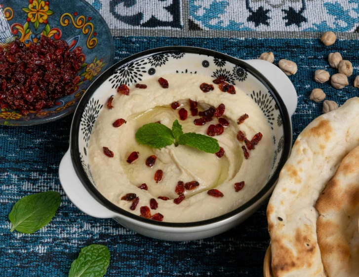 a white bowl of hummus with a leaf on top