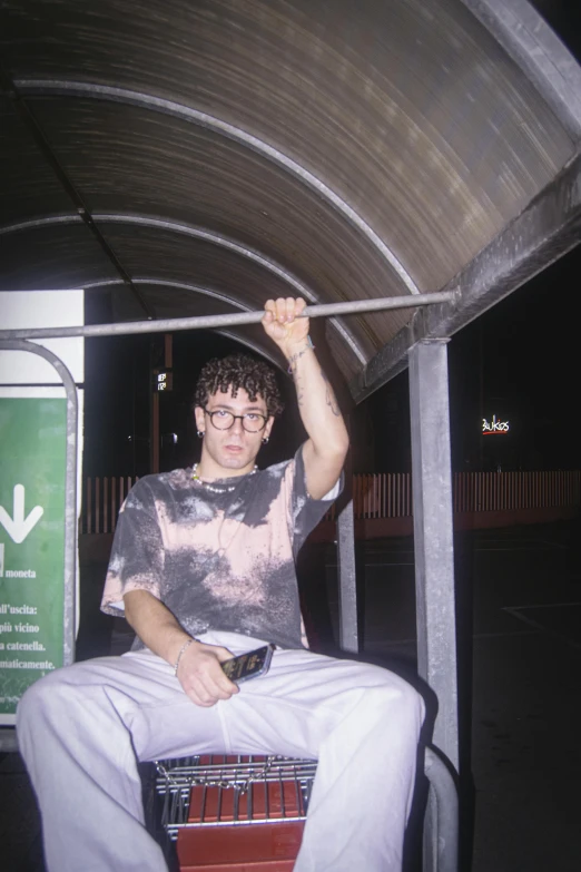 a man with glasses sitting in an open area