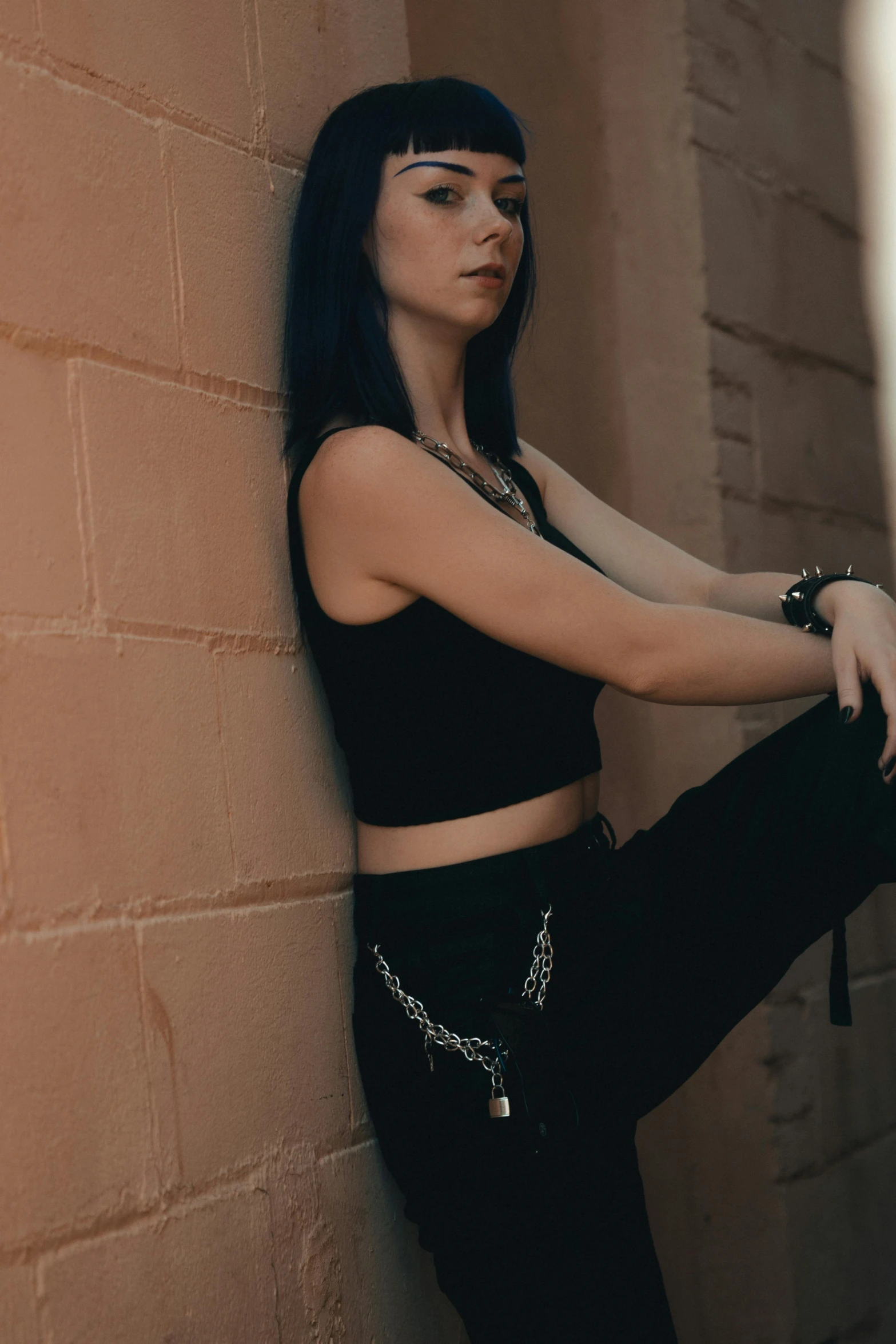 a woman in a top standing next to a wall