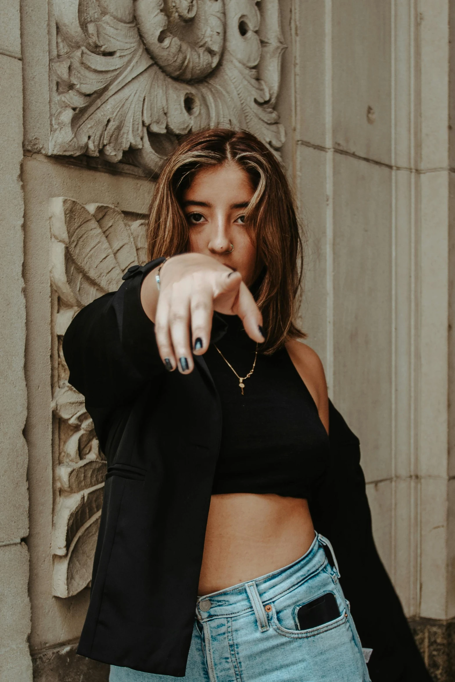 a woman in black shirt pointing towards camera