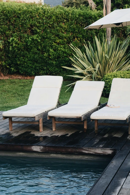 white chaise lounge chairs in front of a private pool