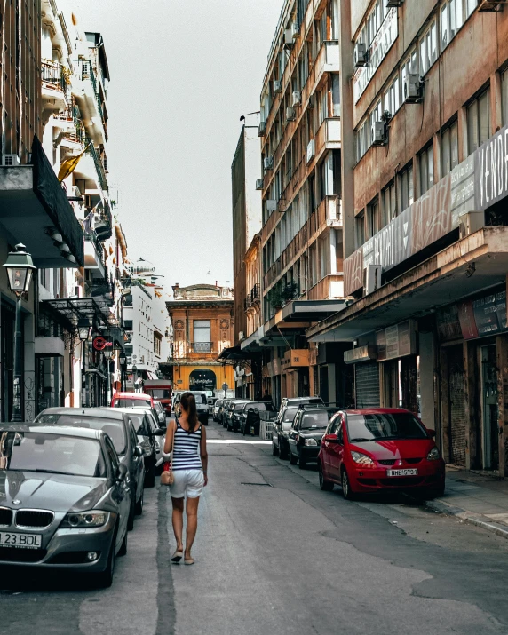 a woman walking down a sidewalk in a city