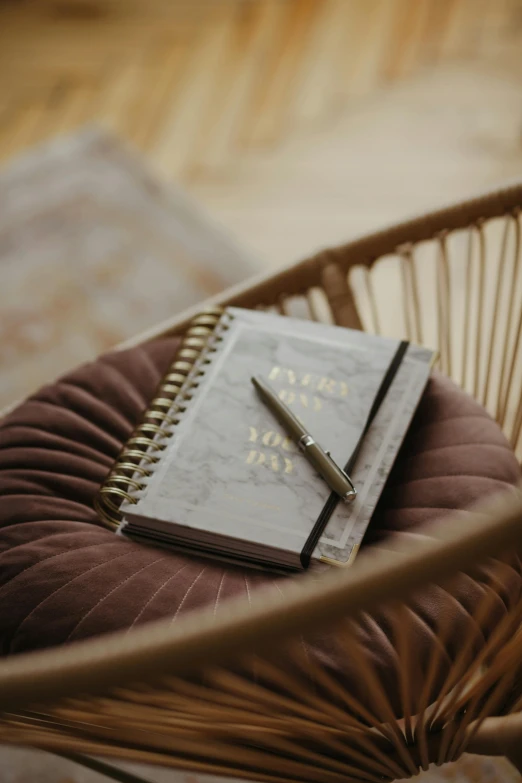 a small notebook sits on a chair with a pen