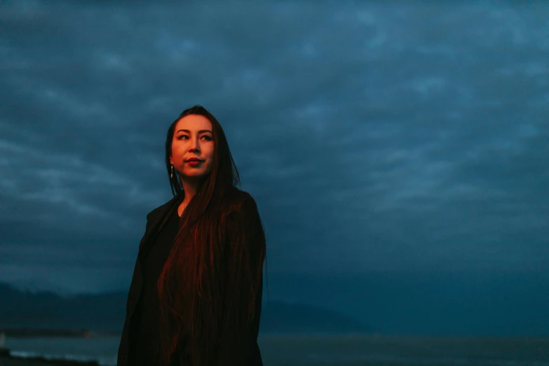 a woman standing in the dark at night, looking at the camera