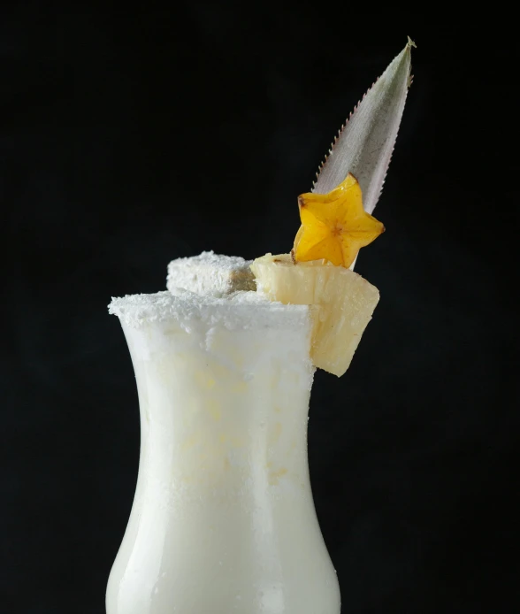 a white vase with yellow flowers and a big leaf