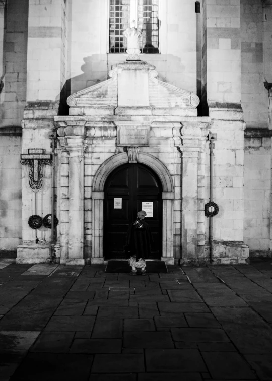 a person stands by the doorway of a large building