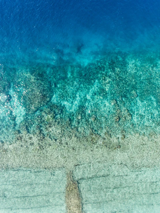 an aerial s of an ocean with rocks in the sand and blue water