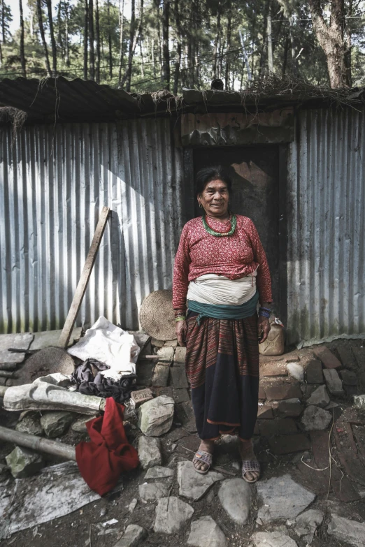 a woman wearing a red dress stands in front of a building with many objects